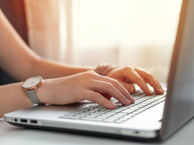 Working from home, contractor, freelance, social media, social marketing concept. Close-up woman's hands typing on laptop keyboard at home. Copy space for text or design