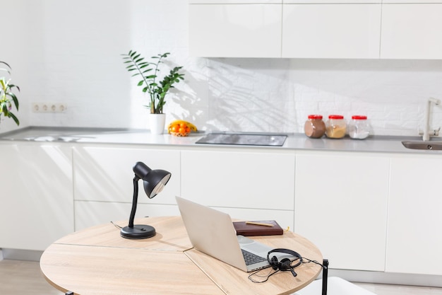 Working from home - a laptop and an organizer on a kitchen table with kitchen in the background.