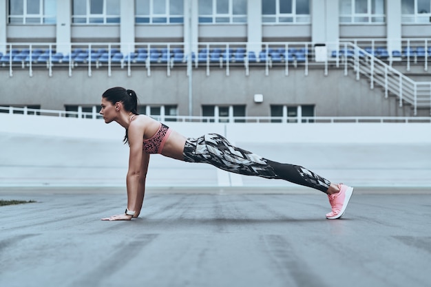 working hard. beautiful young woman in sports clothing keeping plank position 