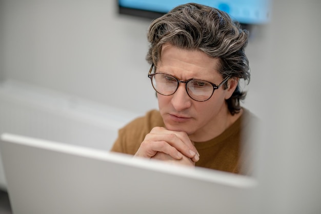 Working. A man sitting at the computer and looking concentrated