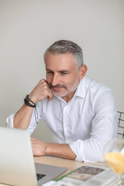 Working. A man in white shirt and eyewear working in the offcie and looking involved