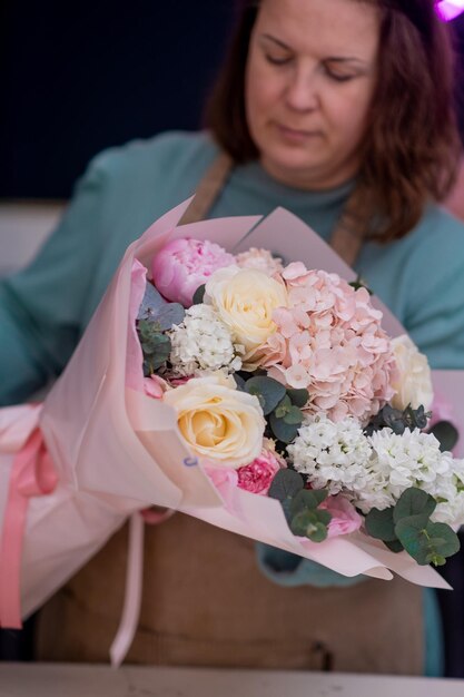 Working in modern floral shop creative female business owner arranges stunning bouquet pink blooms