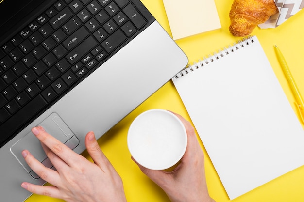 Working morning. Girl works for laptop. Breakfast at work - cappuccino, croissant, notebook