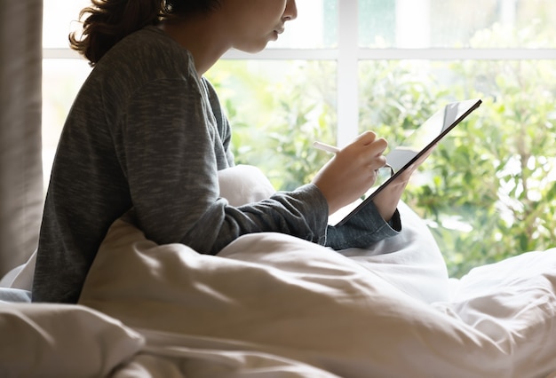 Working at morning Worker women using stylus pen on digital tablet on bed