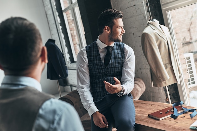 Working on new order. Two young fashionable men having a discussion 