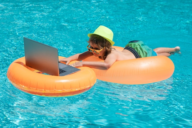 Working and relax on the beach kid working on laptop from the swimming pool summer business