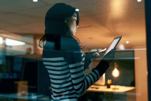 Working tirelessly for the big success she seeks Shot of a young businesswoman working late on a digital tablet in an office