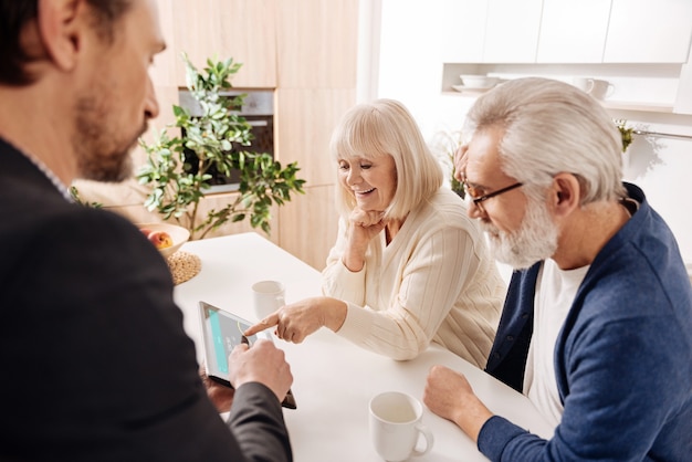 Working with pensioners . Respectable honest diligent real estate agent working with retired couple of clients while demonstrating project and using gadget