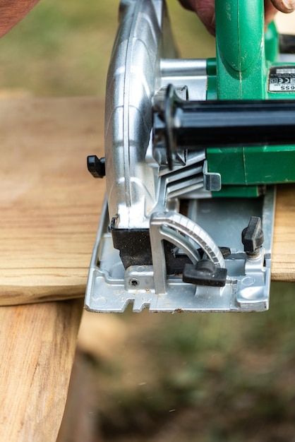 Working with a power tool A builder is sawing a board at the construction site of a wood bench