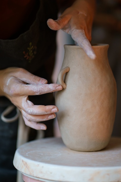 Working with raw clay pottery master add details to potter vase jug artistic occupation in studio