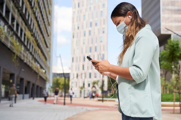 Working woman using a smartphone. He wears a mask for the coronavirus pandemic.