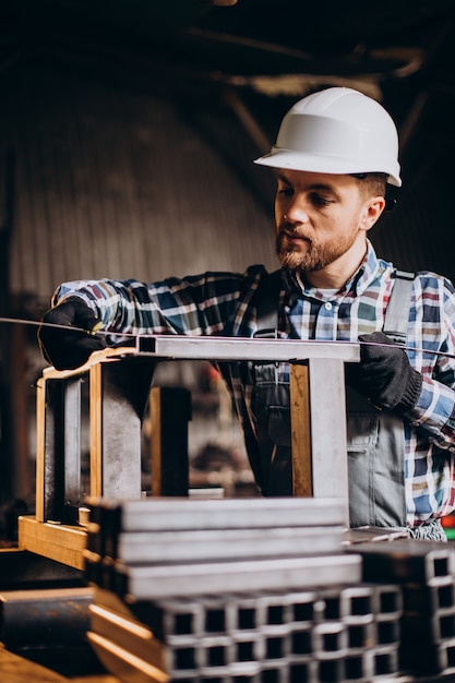 Workman wearing har hat with measuring ruler at factory