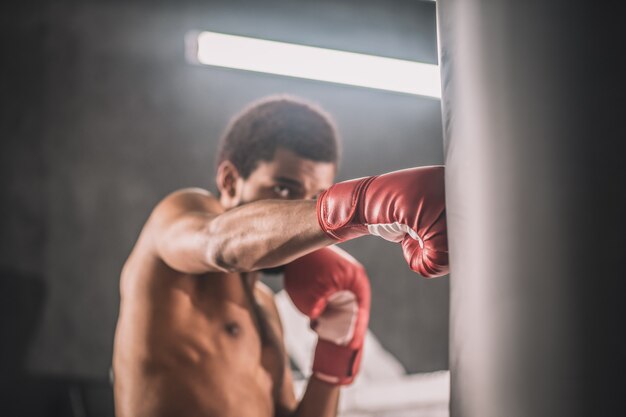 Workout. Dark-skinned kickboxer having a workout in a gym and looking involved