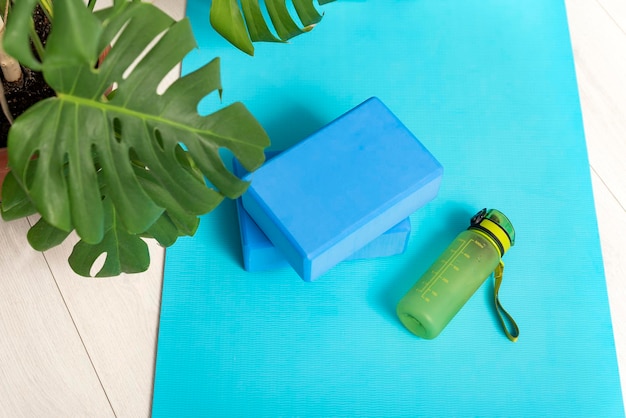 Workout at home. Purple yoga bricks and water bottle on the yoga mat. Instruments for gymnastics and stretching.