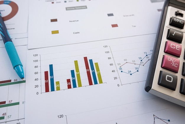 The workplace of business paperwork graph and chart with pen and calculator