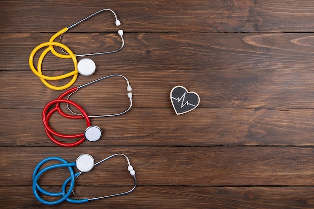 Workplace of a doctor Colorful Stethoscopes and little heart on wooden desk background Healthcare concept