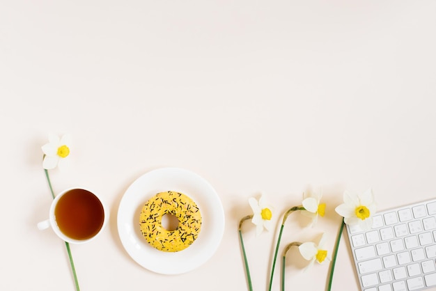 Workplace of a flat lay blogger or freelancer is a woman with a keyboard cup of tea donuts on plate