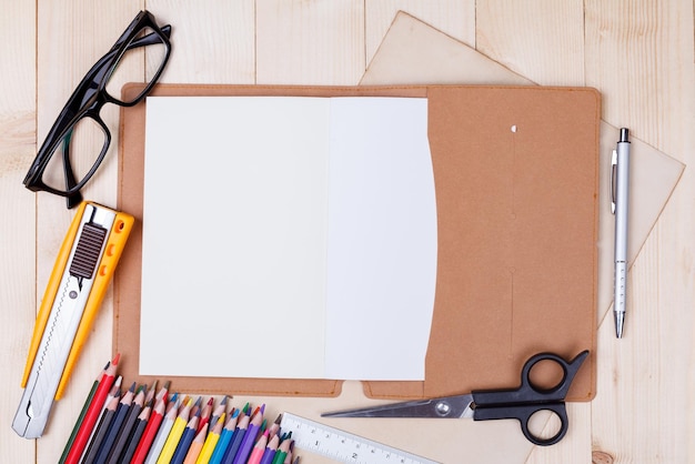 Workplace with colored pencils and supplies notebook eyeglass on wooden table