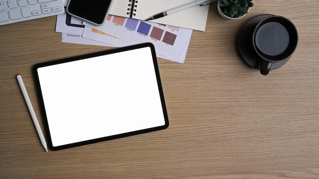 Workplace with digital tablet, stylus pen, smart phone and coffee cup on wooden table.