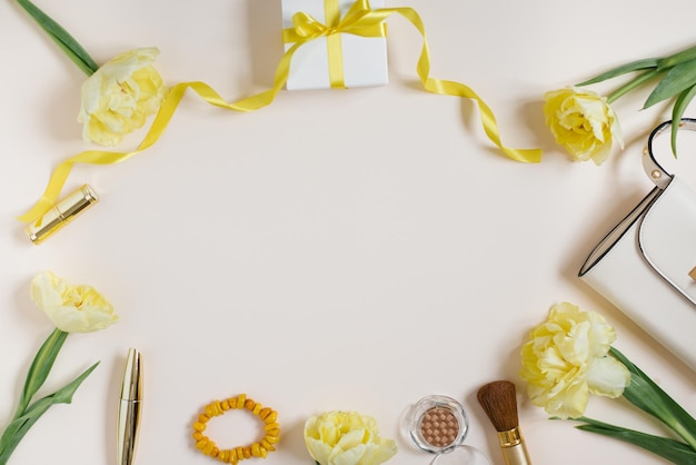 Workspace of a fashionable blogger with a female accessory beauty products yellow tulips flowers