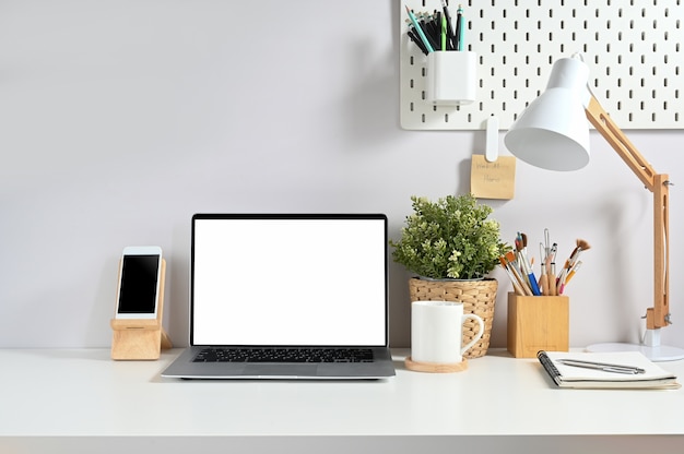 Workspace surround by a white screen laptop and various equipment