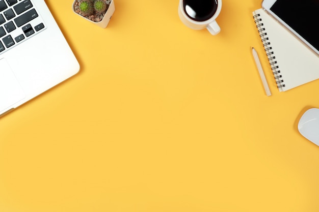 Workspace table with computer and office supplies on yellow