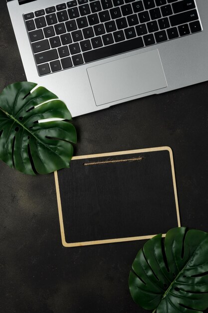 Workspace with blank clip board and laptop on black background Flat lay top view office table desk