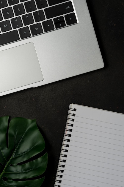 Workspace with blank notebook and laptop on black background Top view with copy space