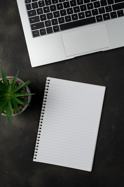 Workspace with blank notebook and laptop on black background Top view with copy space