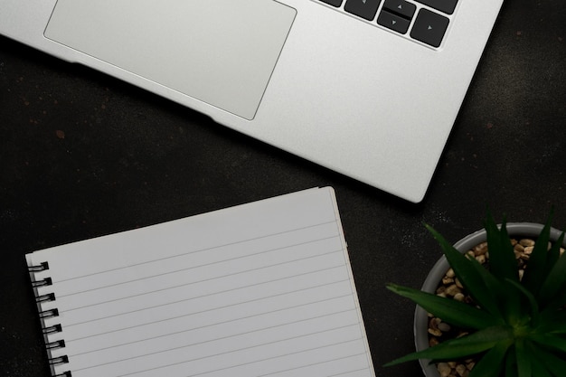 Workspace with blank notebook and laptop on black background Top view with copy space