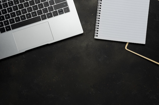 Workspace with blank notebook and laptop on black background Top view with copy space