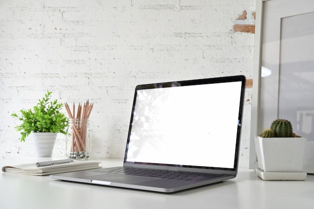 Workspace with blank white screen laptop on loft desk.