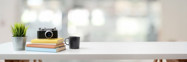 workspace with camera, books, coffee cup, and copy space on white table