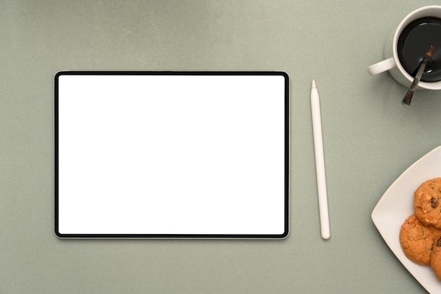 Workspace with digital tablet mockup stylus pen coffee and a plate of cookies on grey background