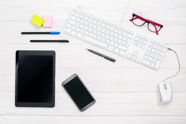 Workspace with keyboard, smartphone, tablet and office supplies on white