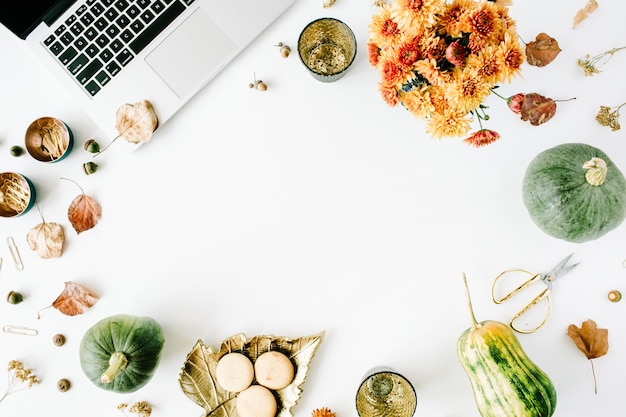 workspace with laptop, chrysanthemum bouquet, pumpkin, leaves, scissors on white