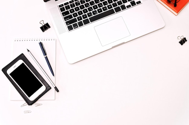 Workspace with laptop keyboard, mobile phone, coffee,  glasses on the white background. Flat lay, top view