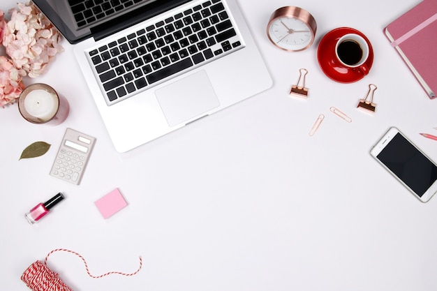 Workspace with pink floral bouquet, smartphone, notebook on white background. 