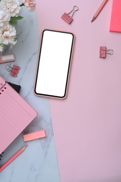 Workspace with smartphone on pink and marble background.