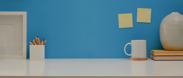 Worktable with copy space stationery and decorations on white desk with blue wall