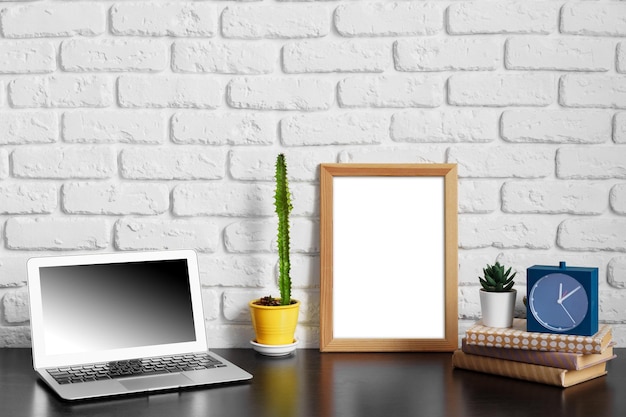 Photo worktable with laptop stationery and decorations in home office with blank photo frame