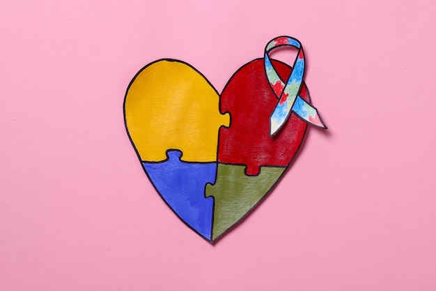 World Autism Awareness Day Ribbon on colorful puzzle heart shape isolated on pink background