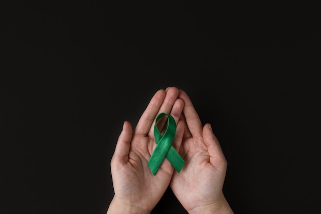 World bipolar day Adult hands holding green ribbon Mental health awareness day