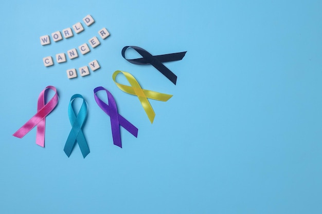 World cancer day  on alphabetic cube arrange with colorful awareness ribbons on blue background