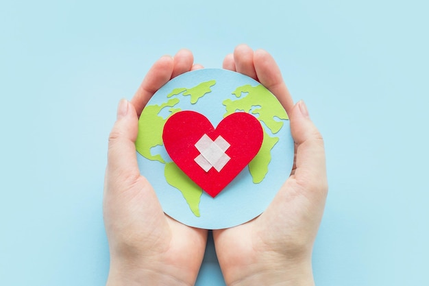 World cardiologist day health day concept Female hands hold a paper model of the globe with a heart