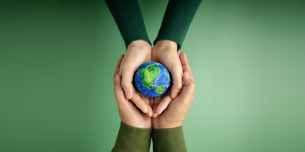 World Earth Day Concept Green Energy ESG Renewable and Sustainable Resources Environmental Care Hands of People Embracing a Handmade Globe Protecting Planet Together Top View