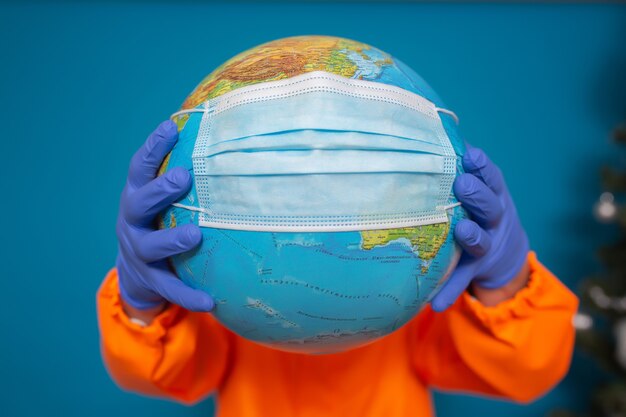 World globe with a medical mask in the hands