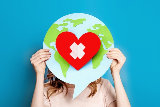 World health day concept Female hands hold a paper model of the globe with a heart