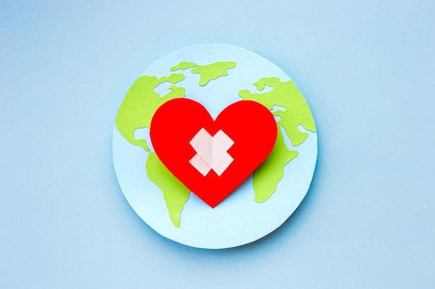 World health day concept Paper model of earth globe heart with cross on blue background