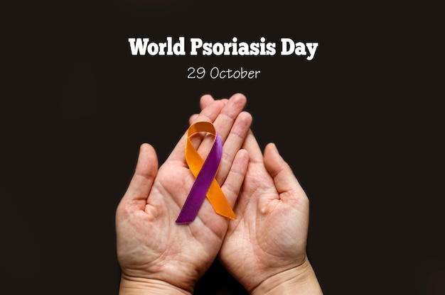 World Psoriasis Day Woman's hands are holding a purpleorange ribbon on a black background